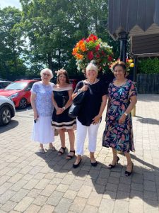 Wetherby 2022. Picture shows four ladies from the YCA stood outside n the sunshine with a hanging basket of flowers behind them.